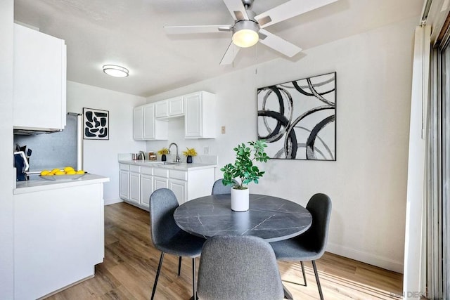 dining room with sink, light hardwood / wood-style floors, and ceiling fan