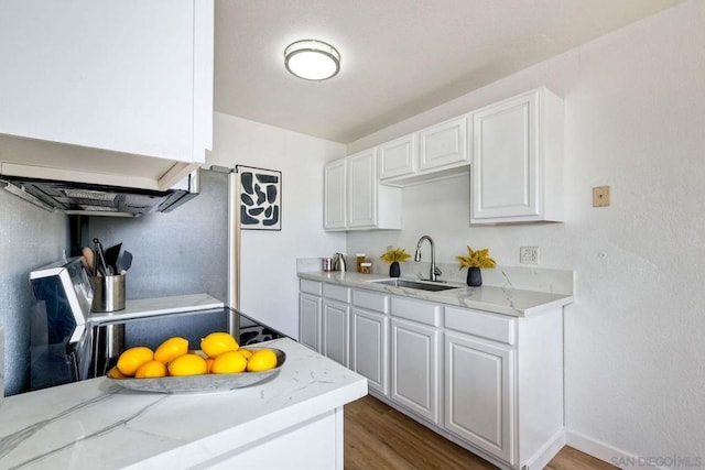 kitchen featuring electric range oven, white cabinetry, sink, hardwood / wood-style flooring, and light stone countertops