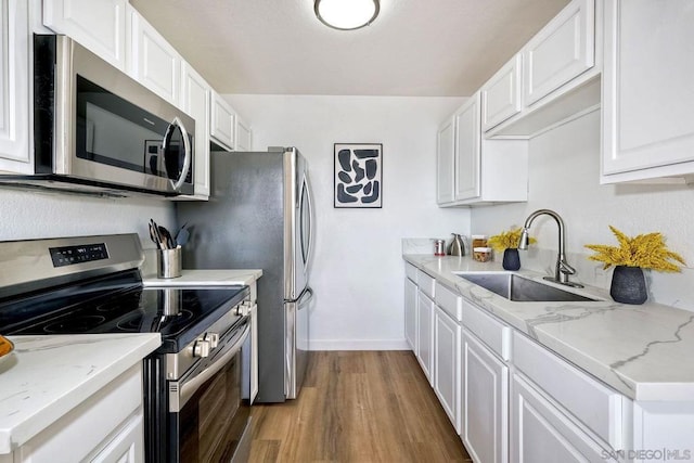 kitchen with white cabinetry, appliances with stainless steel finishes, sink, and light hardwood / wood-style floors