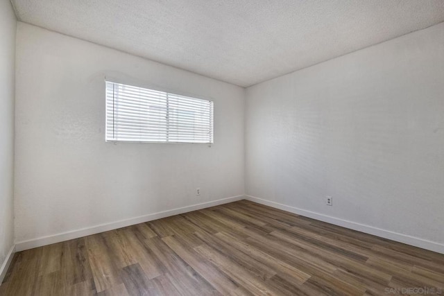 spare room featuring dark hardwood / wood-style floors and a textured ceiling