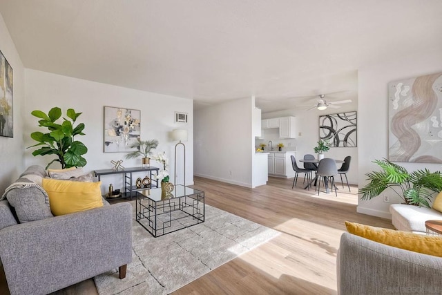 living room featuring sink, light hardwood / wood-style floors, and ceiling fan