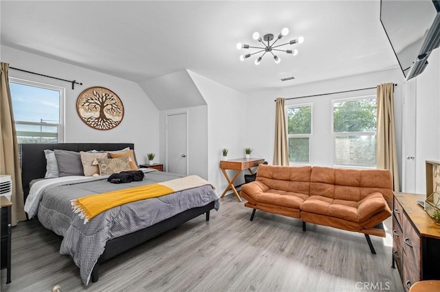 bedroom featuring multiple windows, light hardwood / wood-style flooring, and a chandelier