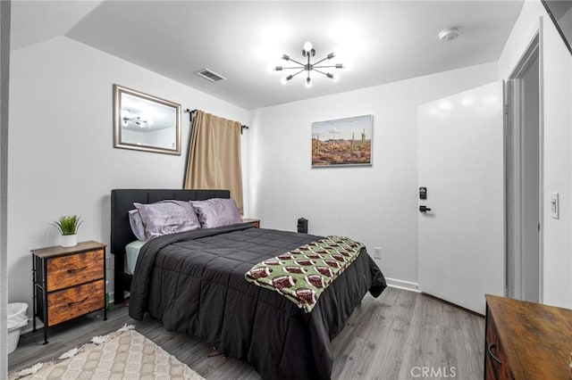 bedroom featuring a chandelier, light hardwood / wood-style floors, and lofted ceiling