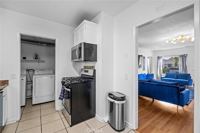 kitchen with separate washer and dryer, white cabinetry, stainless steel appliances, and light wood-type flooring