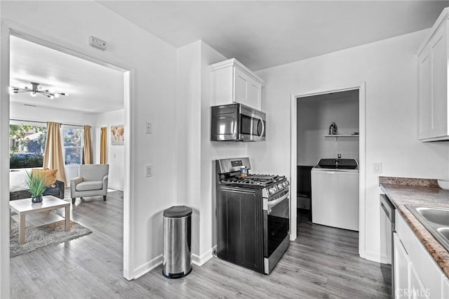 kitchen featuring washer / clothes dryer, light hardwood / wood-style flooring, white cabinets, and stainless steel appliances