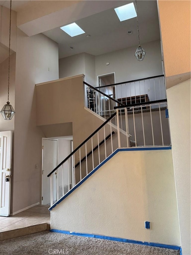 staircase featuring carpet flooring and a high ceiling