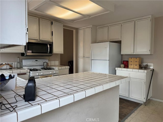 kitchen featuring white cabinetry, white appliances, and tile counters