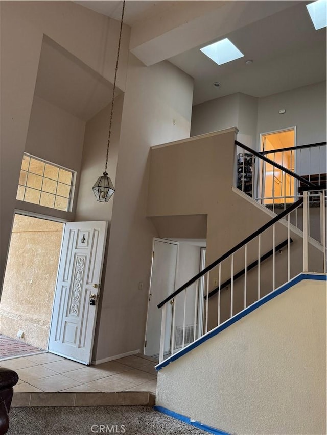 interior space with a towering ceiling, tile patterned floors, and a skylight