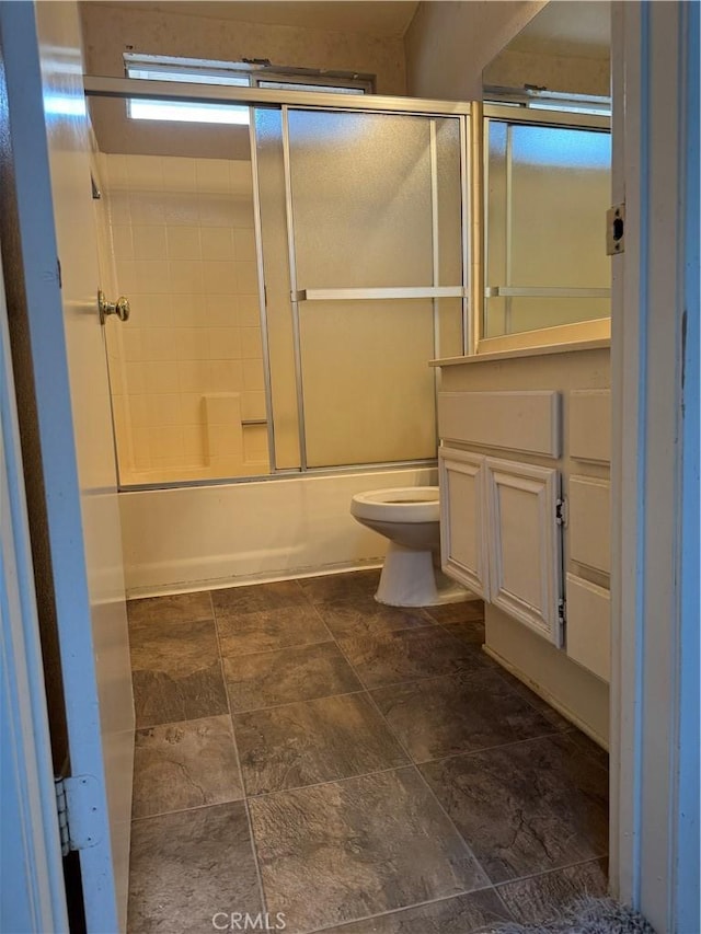 bathroom with toilet and bath / shower combo with glass door