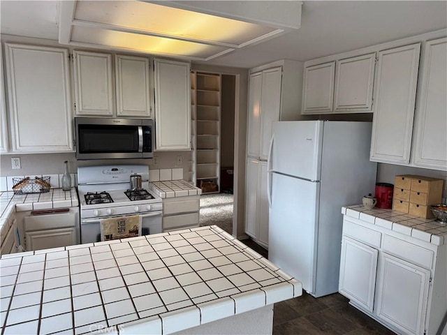 kitchen featuring white cabinetry, white appliances, and tile counters