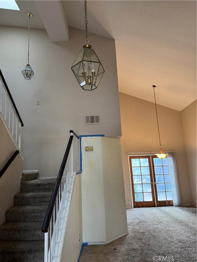 stairs with high vaulted ceiling, french doors, and carpet