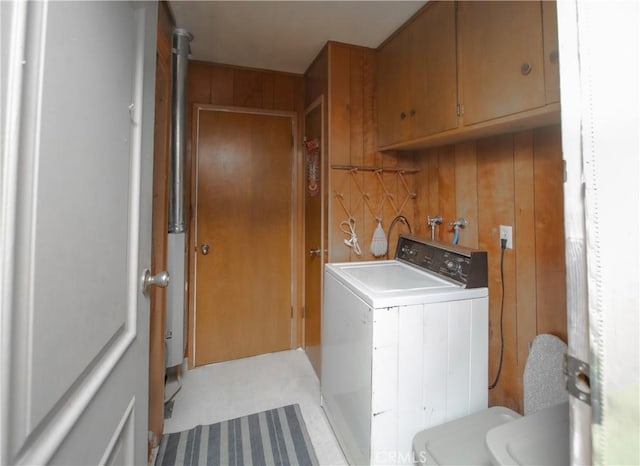 washroom with washer / clothes dryer, cabinets, and wood walls