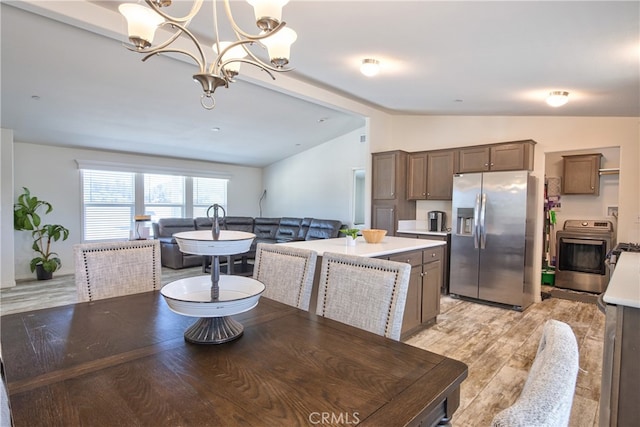 dining space with light hardwood / wood-style flooring, lofted ceiling, and an inviting chandelier