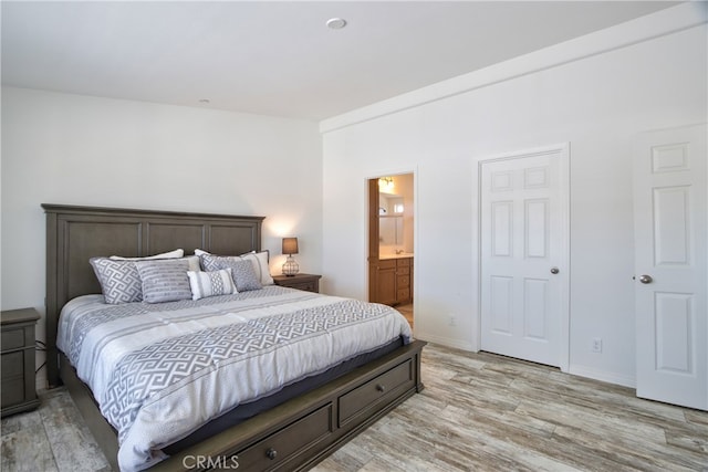 bedroom featuring ensuite bathroom and light hardwood / wood-style flooring