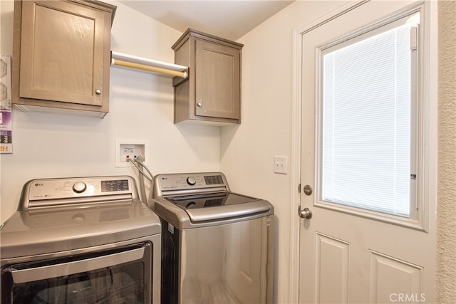 clothes washing area with cabinets and washer and dryer