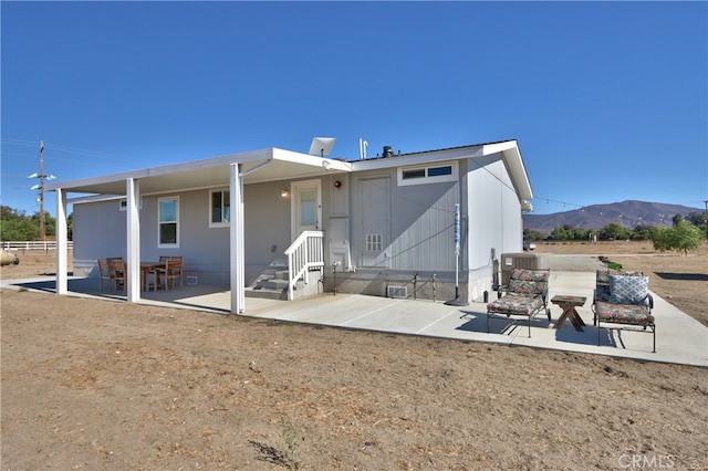 back of property featuring central AC unit, a mountain view, and a patio area