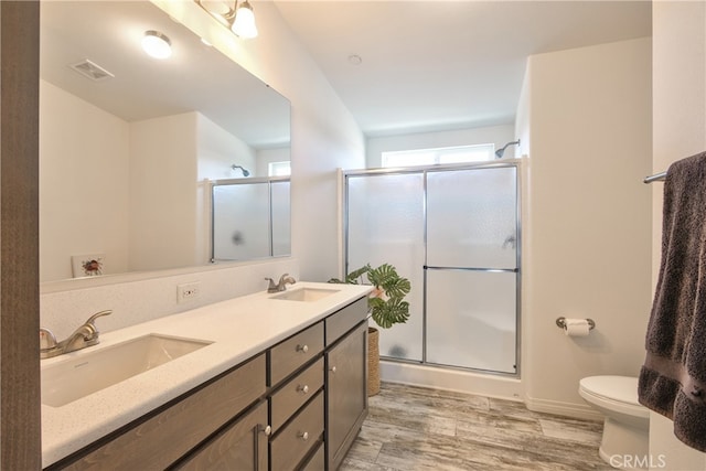 bathroom featuring hardwood / wood-style floors, vanity, toilet, and an enclosed shower