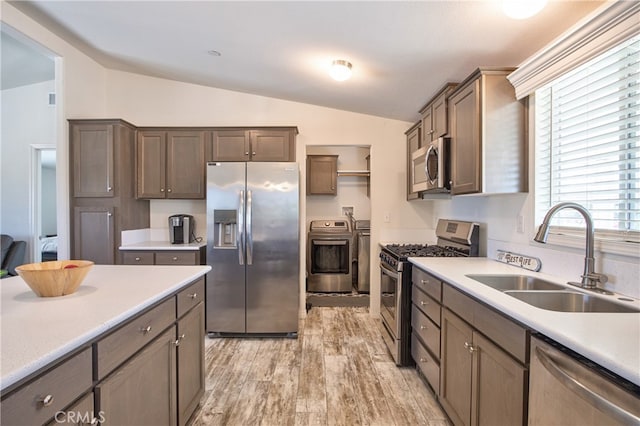 kitchen with washer and clothes dryer, sink, stainless steel appliances, and lofted ceiling