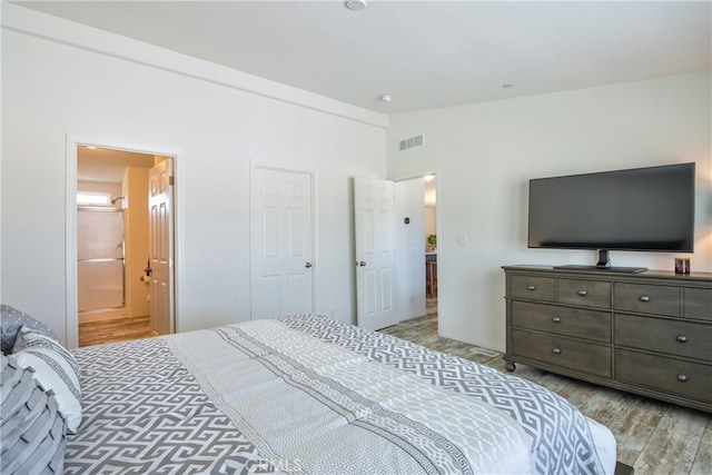 bedroom featuring light wood-type flooring and ensuite bath