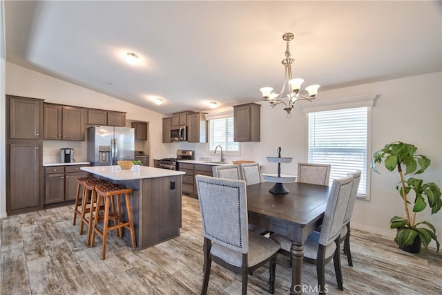 dining area featuring light hardwood / wood-style flooring, vaulted ceiling, and sink