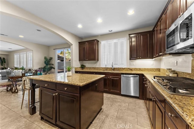 kitchen with dark brown cabinets, a kitchen island, sink, and stainless steel appliances