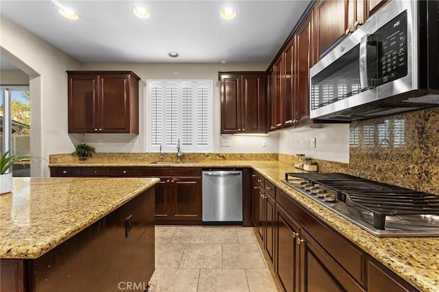 kitchen with sink, light tile patterned floors, appliances with stainless steel finishes, tasteful backsplash, and light stone counters