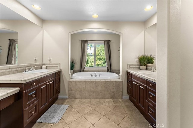 bathroom with tile patterned flooring, vanity, and tiled tub