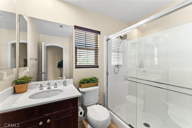 bathroom featuring vanity, an enclosed shower, and toilet