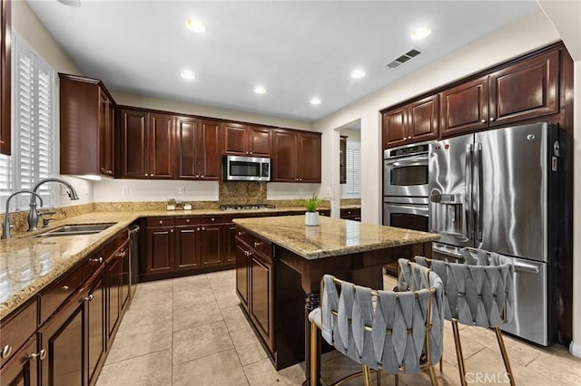 kitchen featuring light stone countertops, sink, a center island, and stainless steel appliances