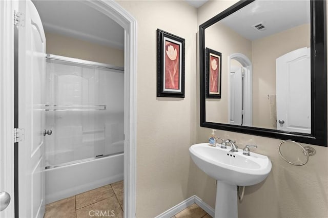 bathroom featuring tile patterned flooring, enclosed tub / shower combo, and sink