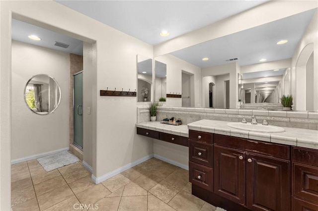 bathroom with tile patterned floors, vanity, a shower with door, and tasteful backsplash