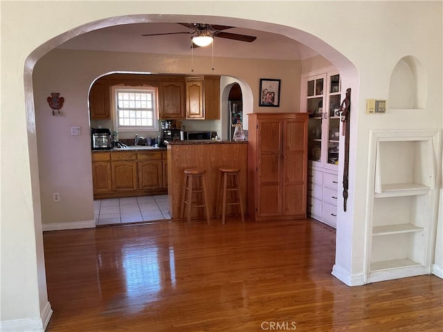 kitchen with ceiling fan, sink, light hardwood / wood-style floors, and built in features