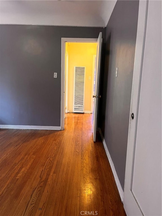 corridor with lofted ceiling and hardwood / wood-style floors