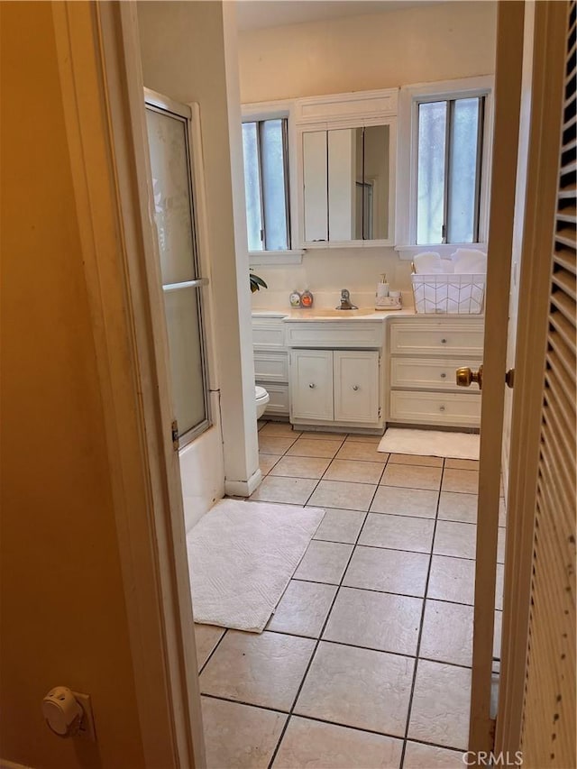 full bathroom featuring tile patterned floors, toilet, combined bath / shower with glass door, and vanity