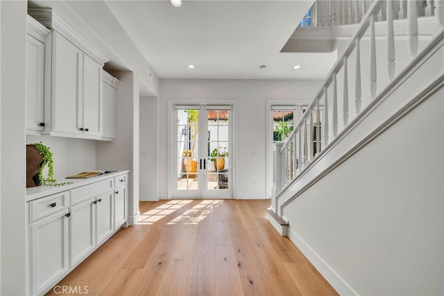 interior space with french doors, white cabinetry, and light hardwood / wood-style floors