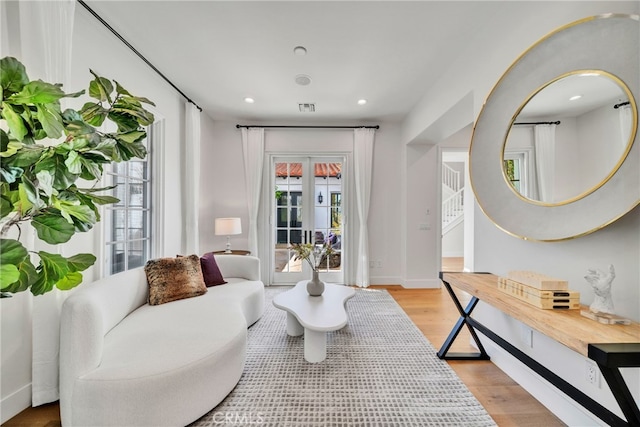 living area with french doors and light hardwood / wood-style floors