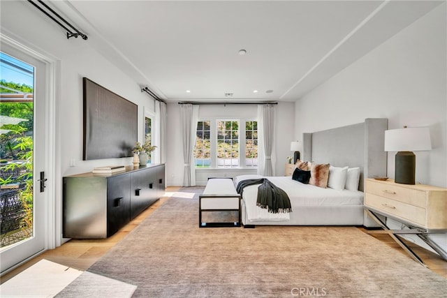 bedroom with access to exterior, multiple windows, and light hardwood / wood-style floors