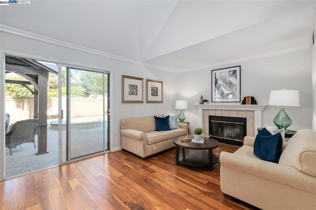 living room featuring crown molding, a fireplace, vaulted ceiling, and hardwood / wood-style flooring