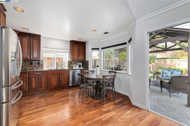 kitchen featuring sink, light hardwood / wood-style flooring, decorative backsplash, ornamental molding, and appliances with stainless steel finishes