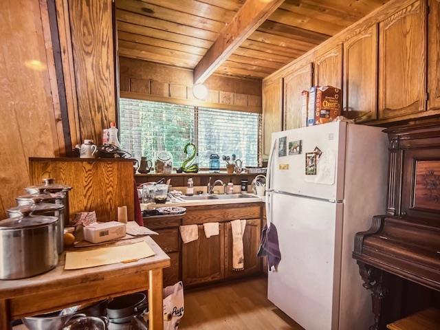 kitchen featuring sink, light wood-type flooring, wooden ceiling, white fridge, and beam ceiling