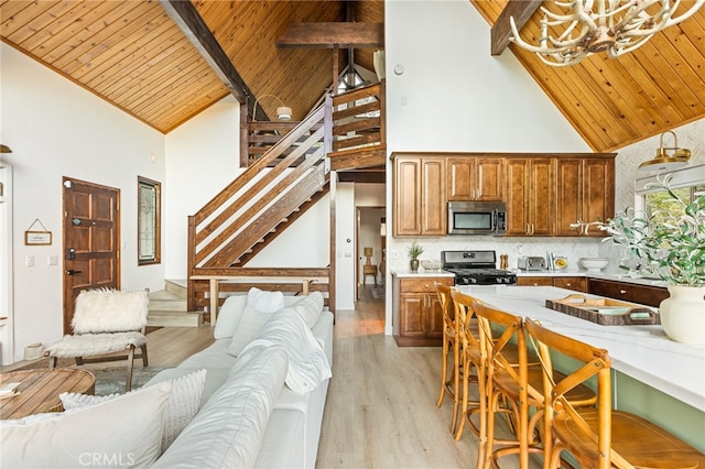 kitchen featuring tasteful backsplash, wood ceiling, black gas range, high vaulted ceiling, and light hardwood / wood-style flooring