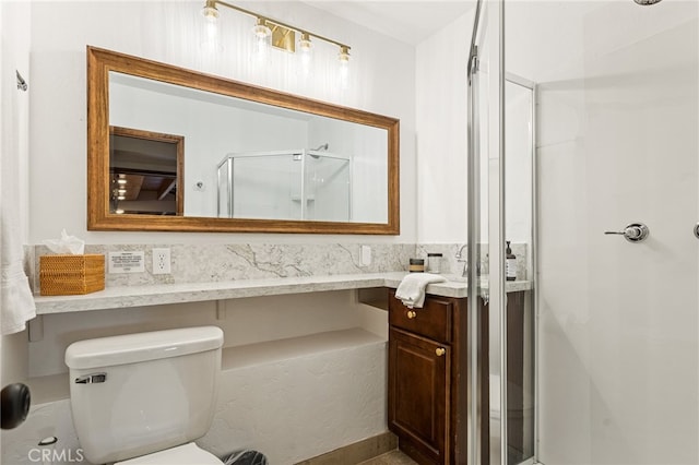 bathroom featuring toilet, vanity, and a shower with door