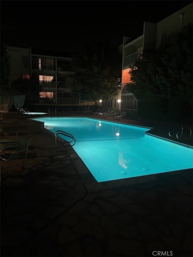 pool at twilight featuring a patio area