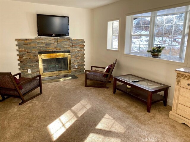 living room with carpet and a stone fireplace