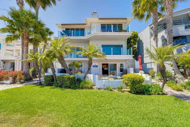 view of front of property with a balcony and a front lawn