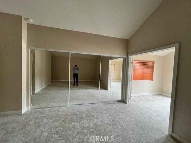 unfurnished bedroom featuring carpet flooring, a closet, and vaulted ceiling