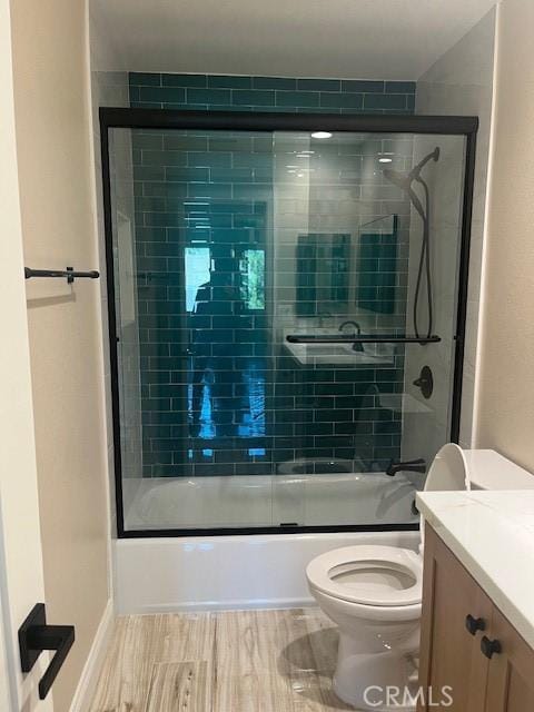 full bathroom with shower / bath combination with glass door, wood-type flooring, vanity, and toilet