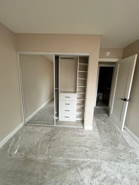 unfurnished bedroom with light carpet and a closet