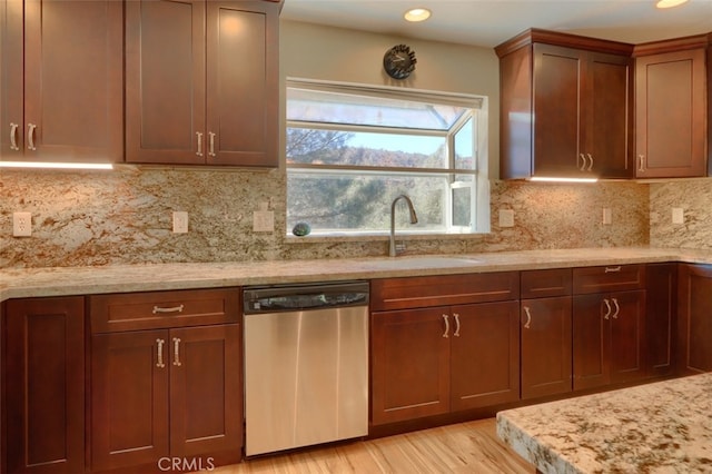 kitchen featuring sink, dishwasher, light stone counters, decorative backsplash, and light hardwood / wood-style flooring