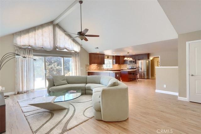 living room featuring beamed ceiling, sink, light wood-type flooring, high vaulted ceiling, and ceiling fan